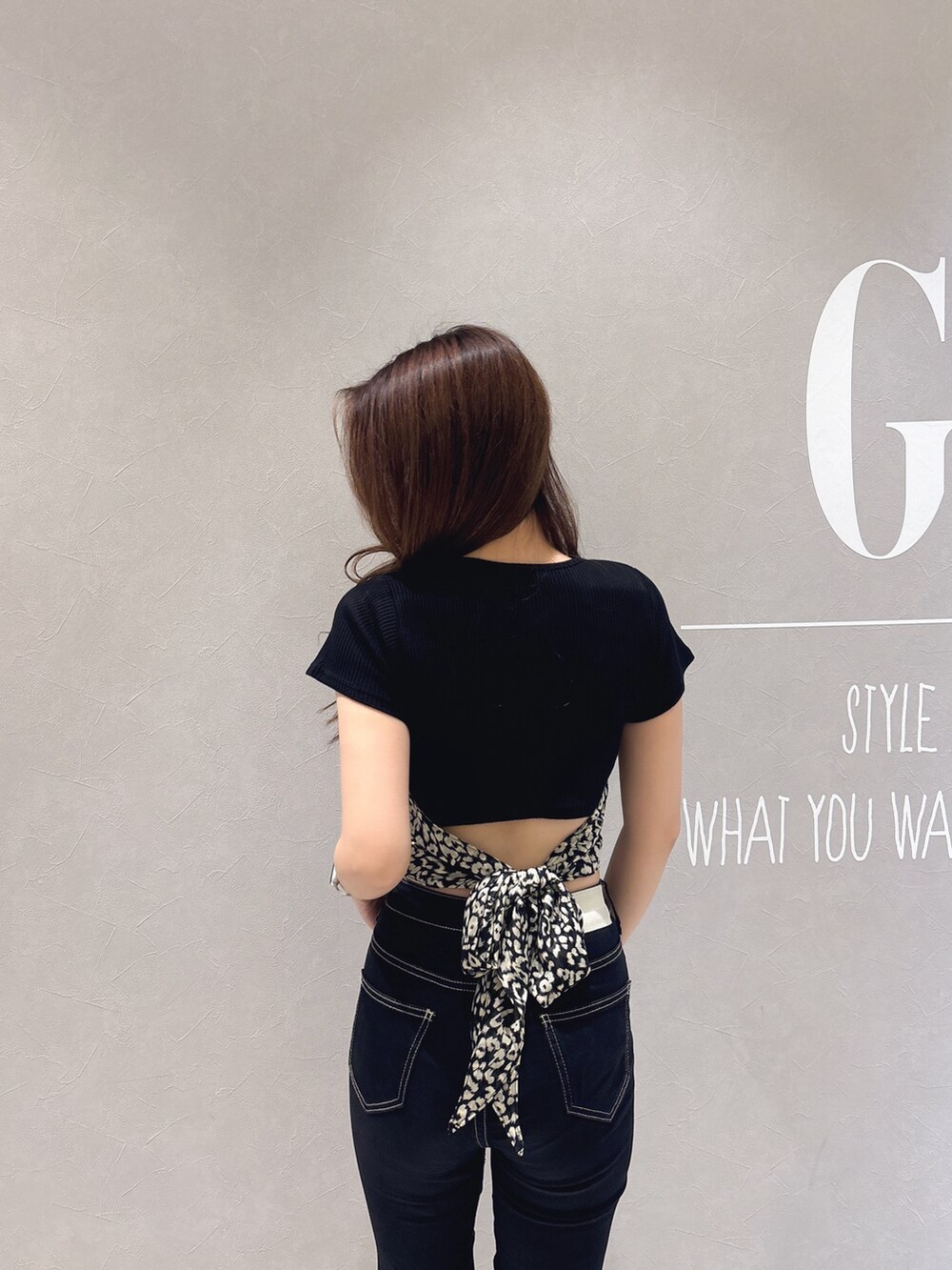 ブラック系のTシャツ/カットソー、ブラック系のデニムパンツ、ホワイト系のパンプスを着用したレディースの春コーディネートの6枚目の写真