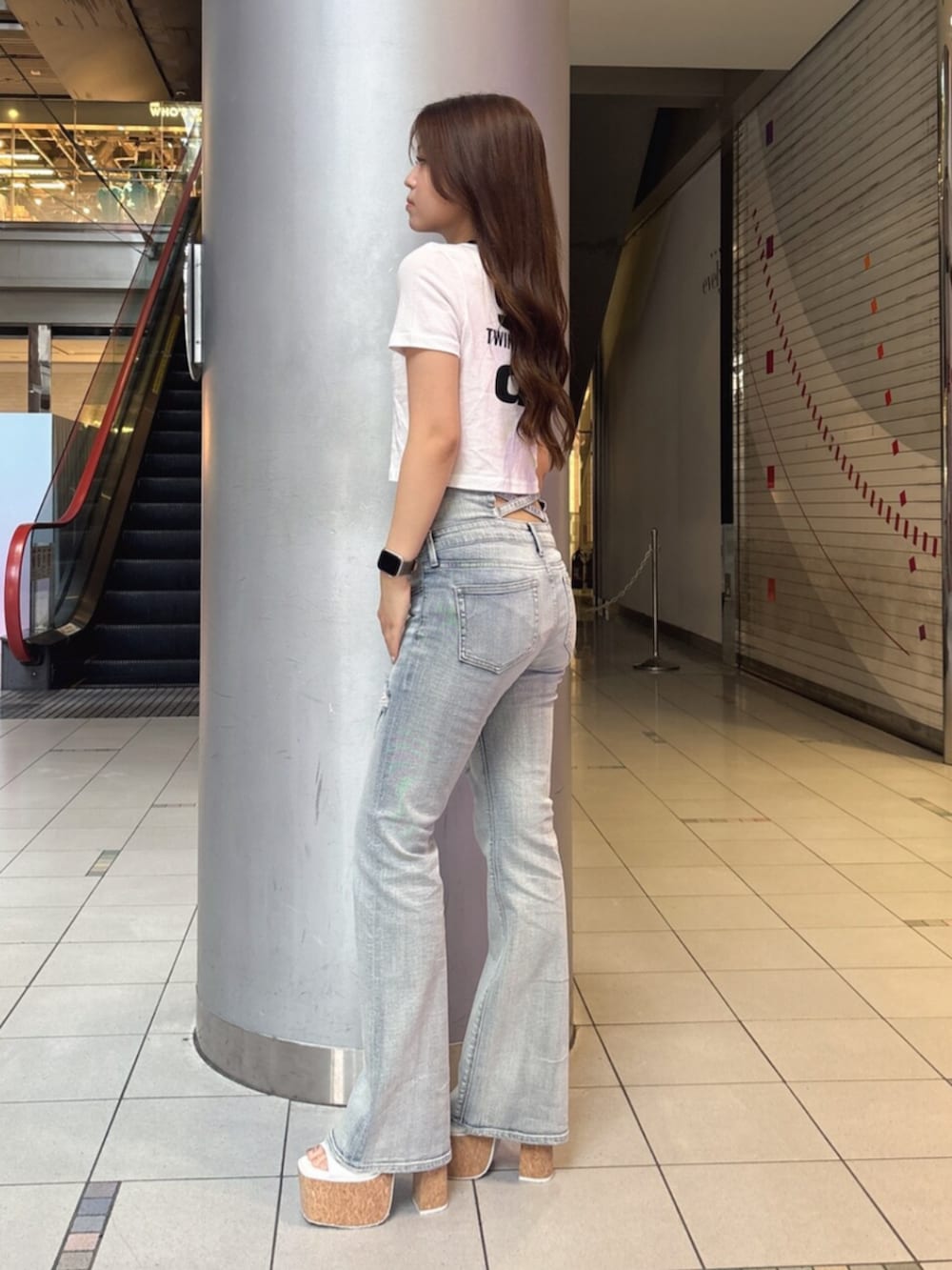 ブルー系のデニムパンツ、ホワイト系のサンダル、ホワイト系のTシャツ/カットソーを着用したレディースの夏コーディネートの2枚目の写真