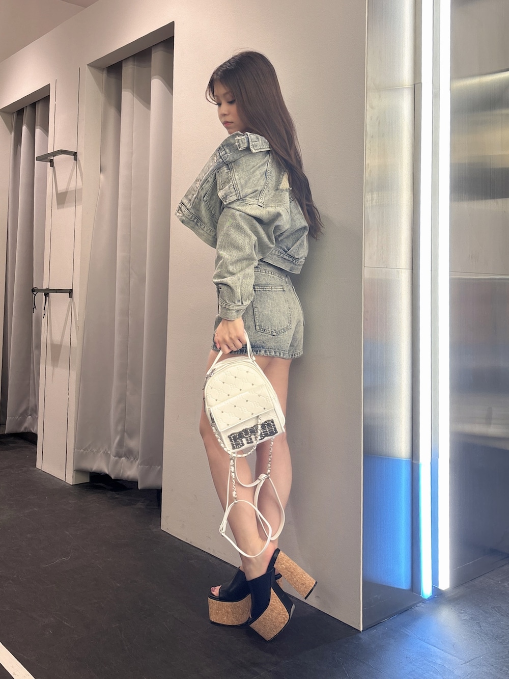 ブルー系のデニムジャケット、ブルー系のデニムパンツ、ホワイト系のバックパック/リュックを着用したレディースの夏コーディネートの2枚目の写真