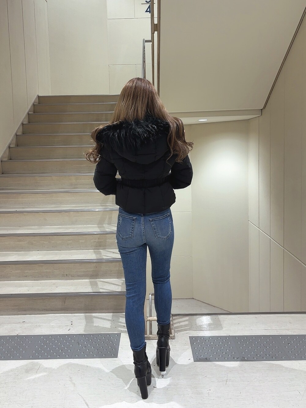 ブラック系のダウンジャケット/コート、ホワイト系のニット/セーター、ブルー系のデニムパンツを着用したレディースの秋コーディネートの2枚目の写真