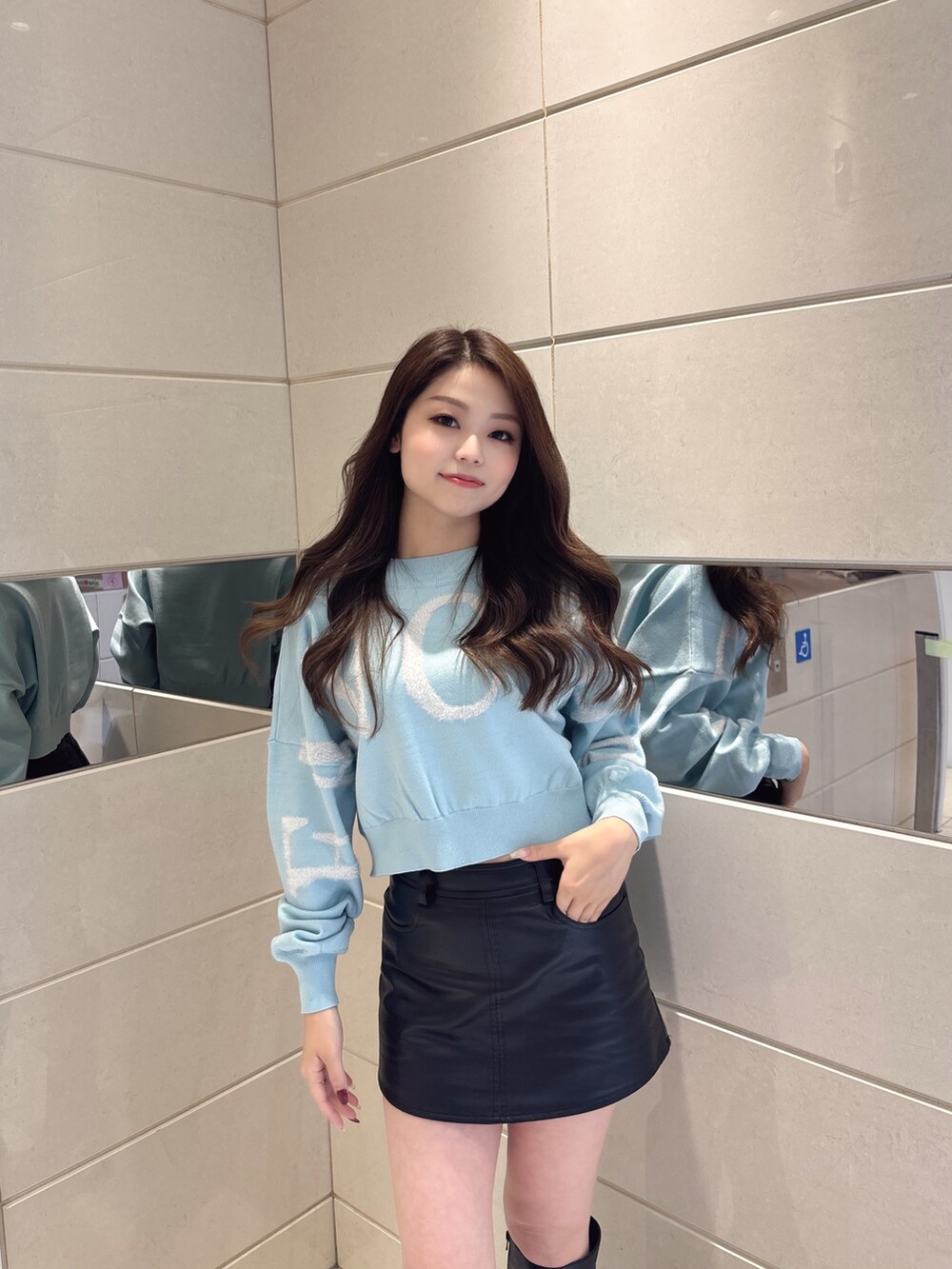 ブルー系のニット/セーター、ブラック系のスカート、ブラック系のブーツを着用したレディースの冬コーディネートの4枚目の写真