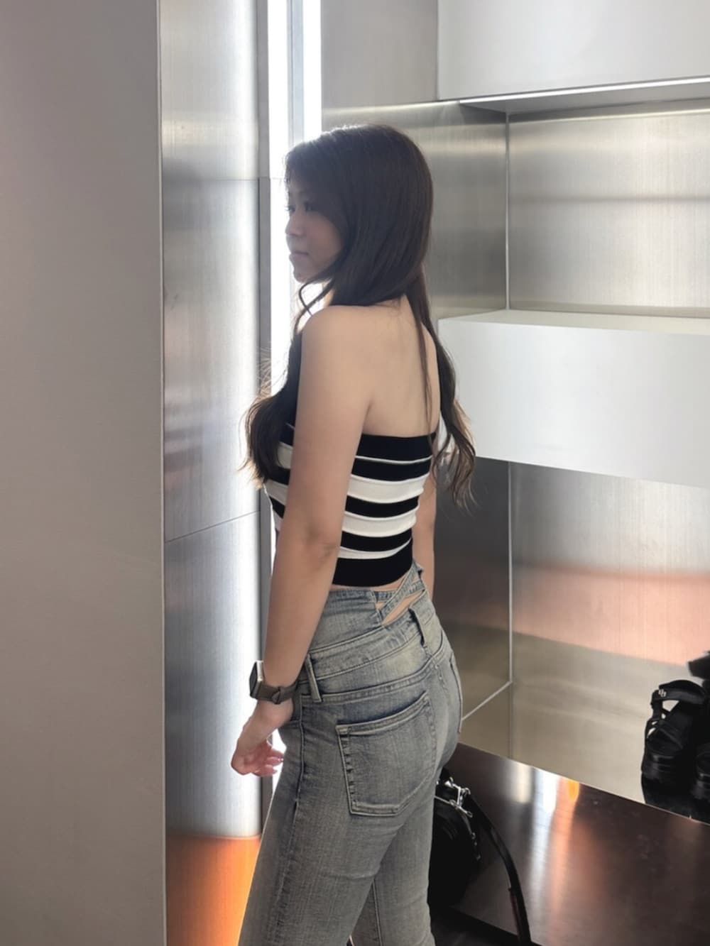 ブルー系のデニムパンツ、ホワイト系のサンダル、ブラック系のハンドバッグを着用したレディースの夏コーディネートの5枚目の写真