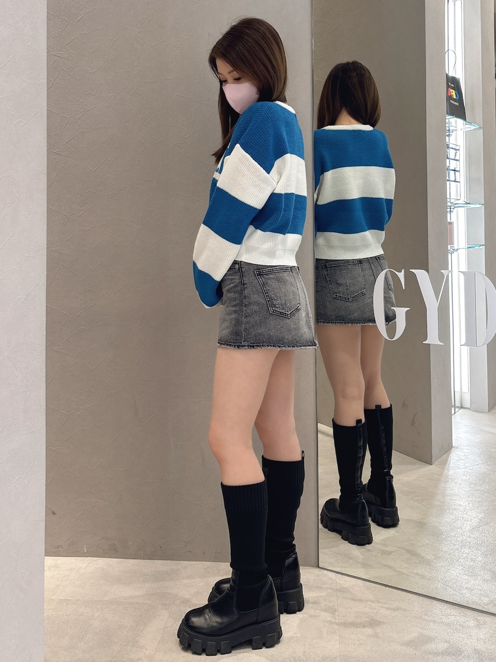 ブルー系のニット/セーター、ブルー系のデニムスカート、ブラック系のブーツを着用したレディースの秋コーディネートの2枚目の写真