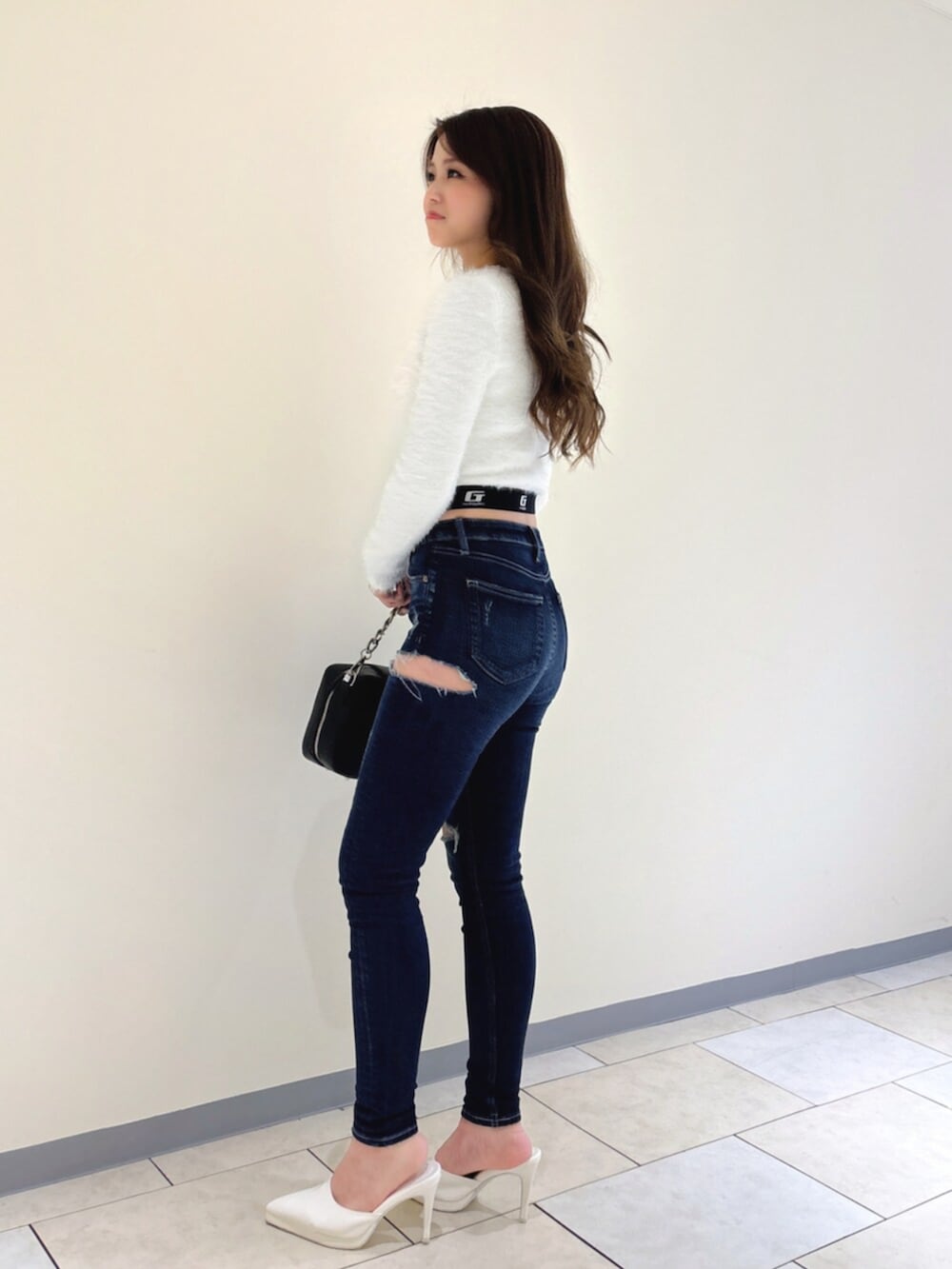 ホワイト系のパンプス、ブルー系のデニムパンツ、ブラック系のショルダーバッグを着用したレディースの冬コーディネートの3枚目の写真