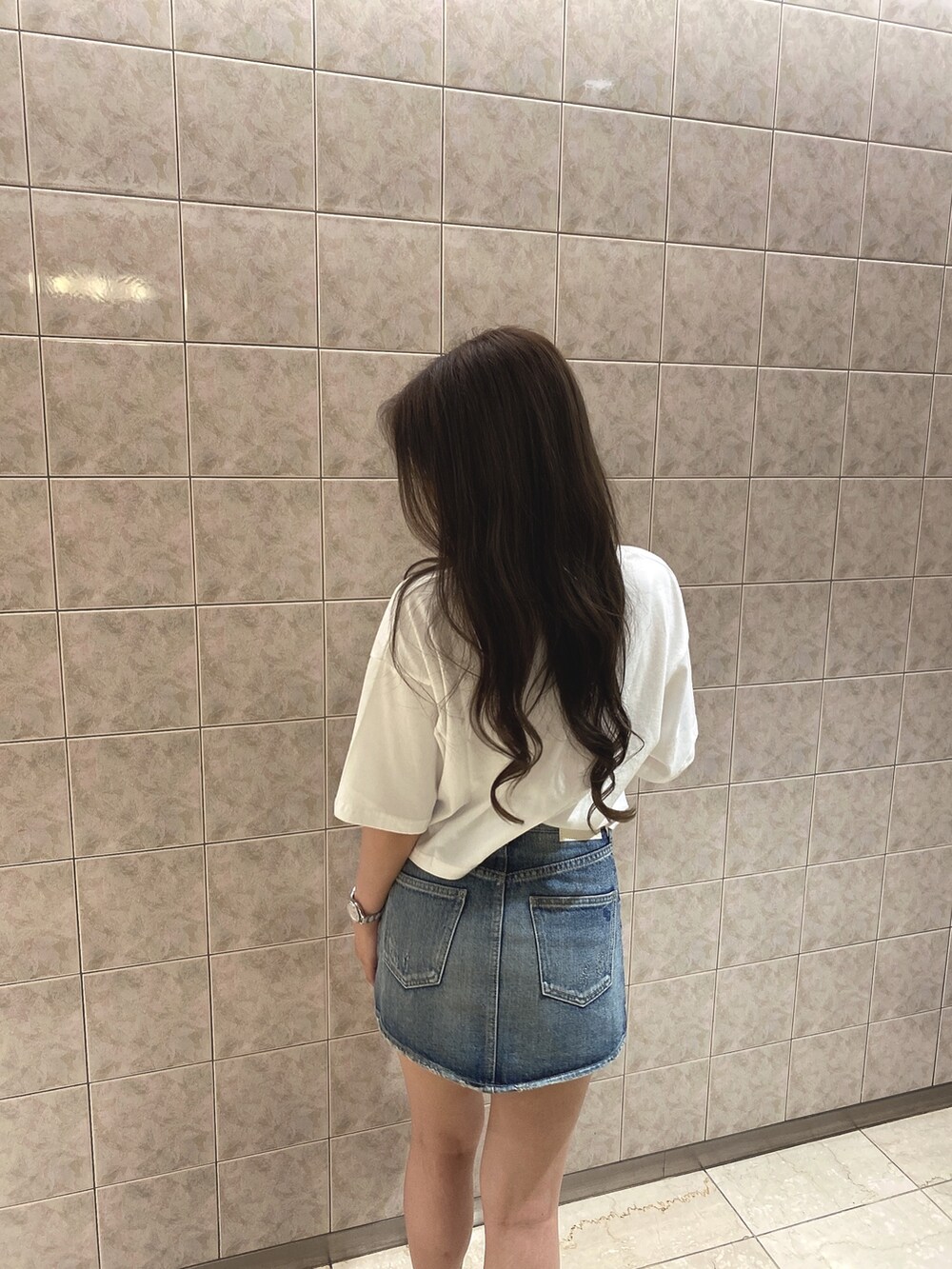 ホワイト系のTシャツ/カットソー、ブルー系のデニムスカート、ホワイト系のブーツを着用したレディースの夏コーディネートの6枚目の写真