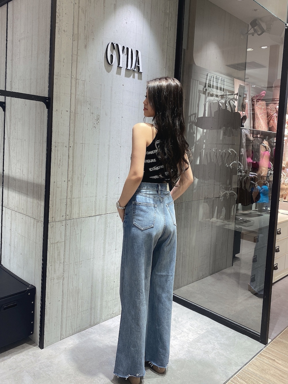 ブラック系のニット/セーター、ホワイト系のサンダル、ブルー系のデニムパンツを着用したレディースの春コーディネートの4枚目の写真