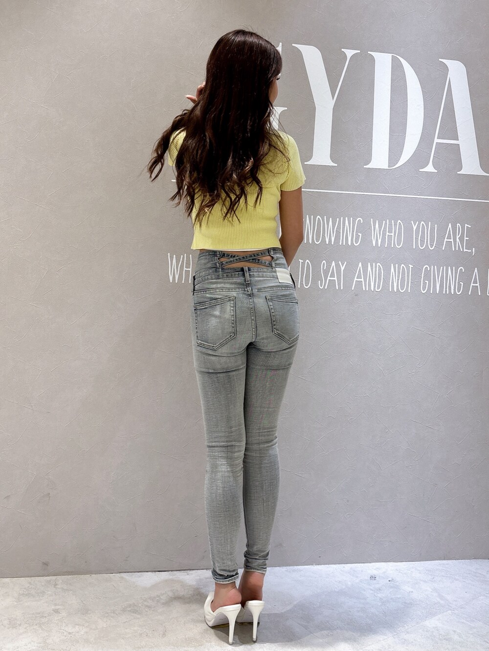 イエロー系のニット/セーター、ブルー系のデニムパンツ、ホワイト系のパンプスを着用したレディースの春コーディネートの3枚目の写真