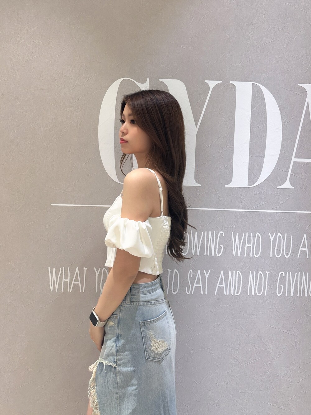 ホワイト系のシャツ/ブラウス、ブルー系のデニムスカート、ブラック系のサンダルを着用したレディースの春コーディネートの6枚目の写真