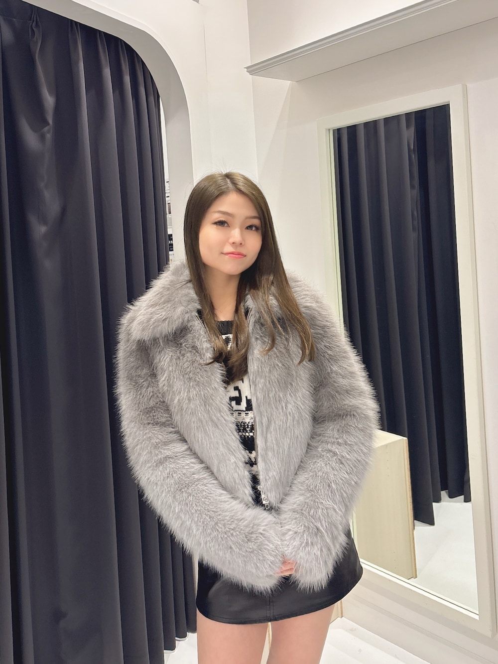 グレー系のダウンジャケット/コート、ブラック系のスカート、ブラック系のブーツを着用したレディースの秋コーディネートの4枚目の写真