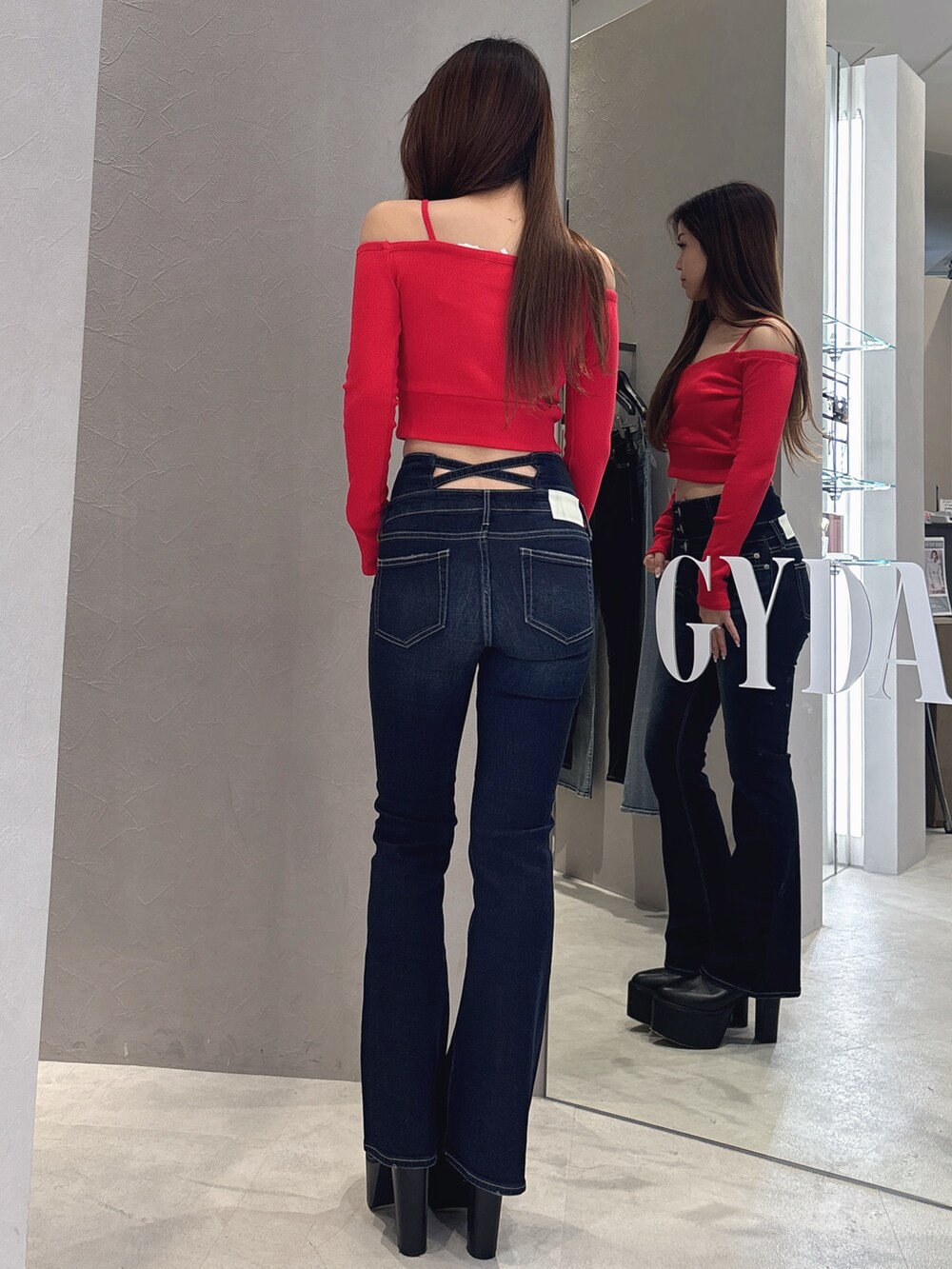 レッド系のTシャツ/カットソー、ブルー系のデニムパンツ、ブラック系のブーツを着用したレディースの秋コーディネートの3枚目の写真