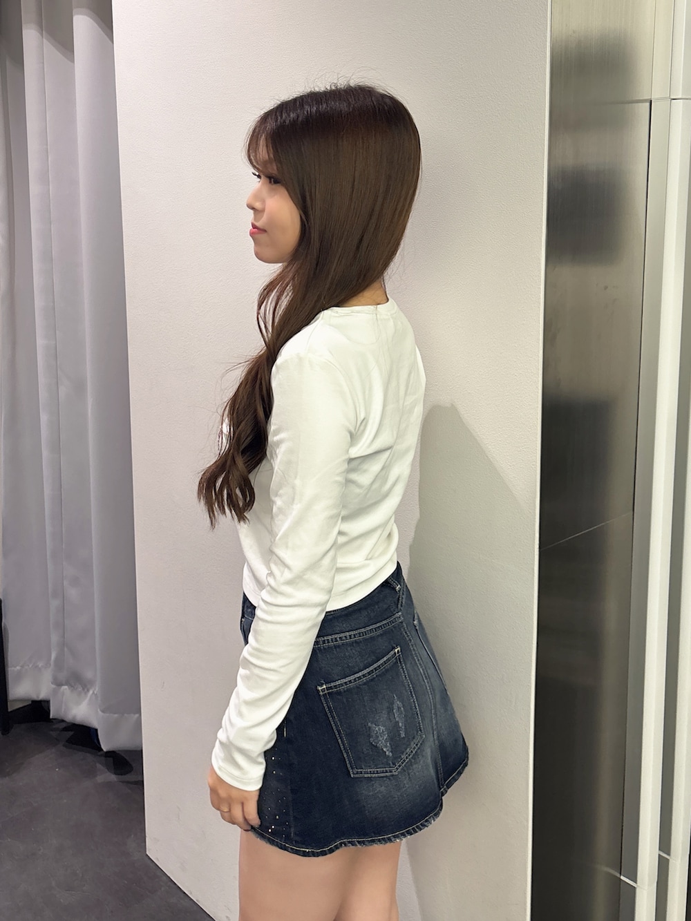 ホワイト系のTシャツ/カットソー、ブルー系のデニムスカート、ブラック系のバックパック/リュックを着用したレディースの秋コーディネートの5枚目の写真
