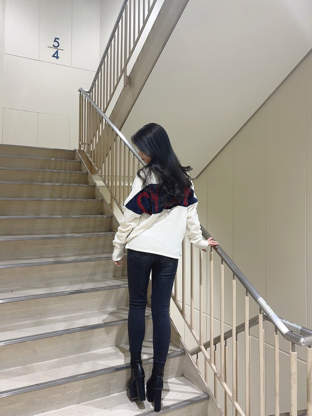 ホワイト系のニット/セーター、ブラック系のデニムパンツ、ブラック系のブーツを着用したレディースの秋コーディネートの2枚目の写真