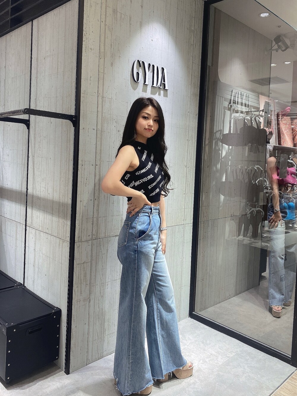 ブラック系のニット/セーター、ホワイト系のサンダル、ブルー系のデニムパンツを着用したレディースの春コーディネートの2枚目の写真