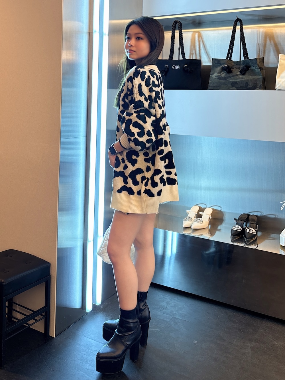 ブルー系のワンピース、ホワイト系のカーディガン/ボレロ、ブラック系のブーツを着用したレディースの春コーディネートの2枚目の写真