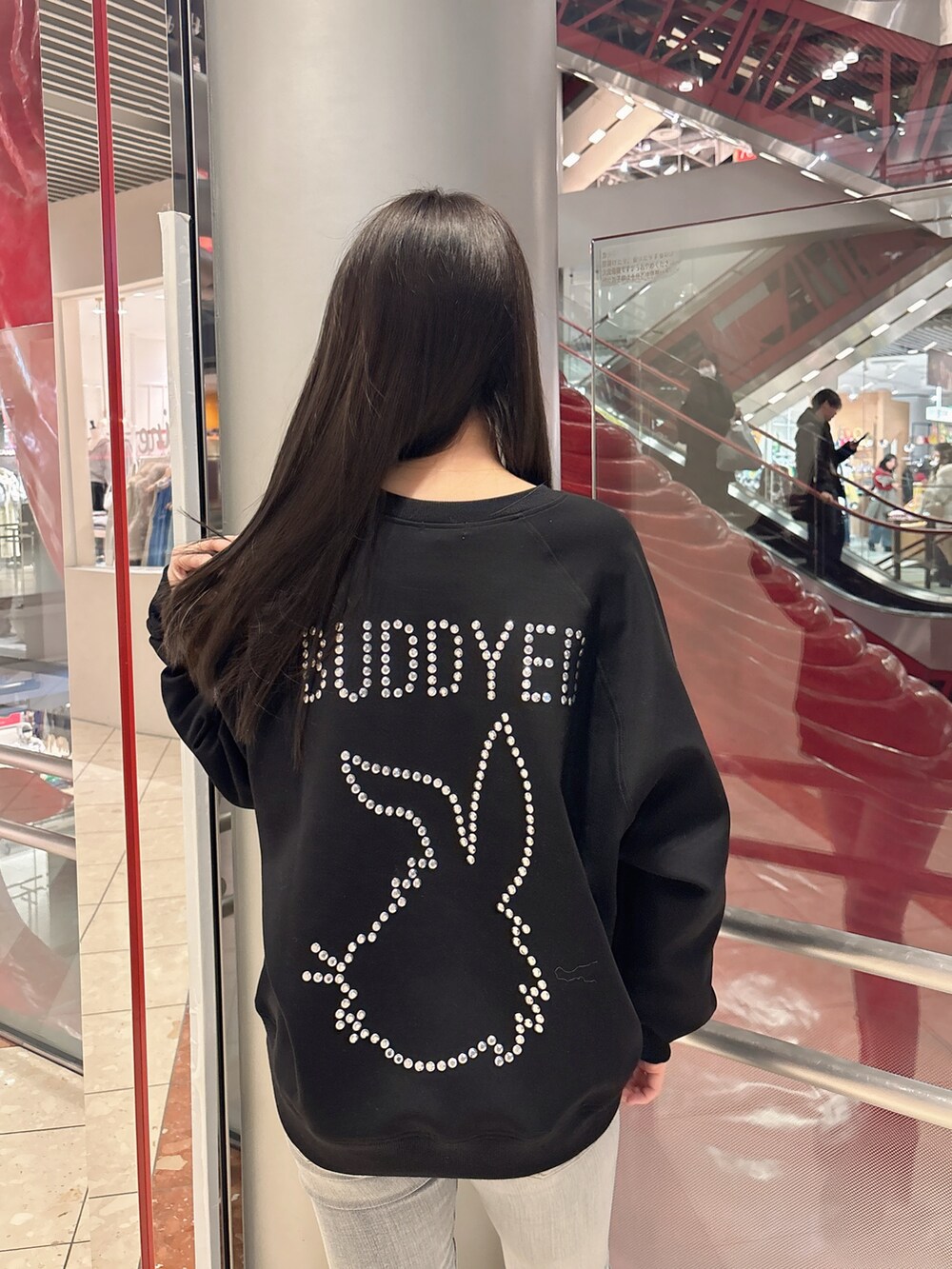 ブラック系のスウェット、ブルー系のデニムパンツ、ブラック系のブーツを着用したレディースの冬コーディネートの6枚目の写真