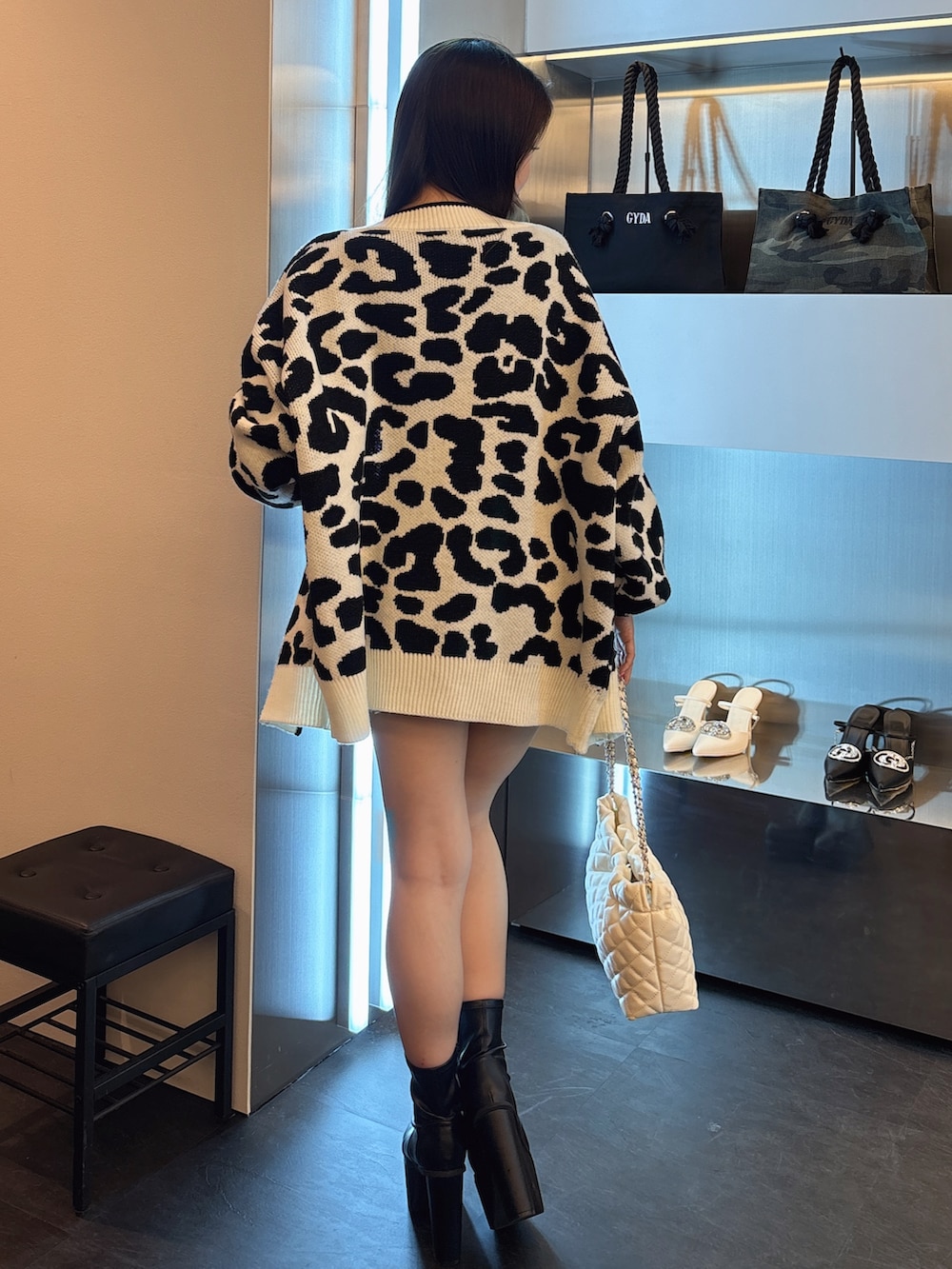 ブルー系のワンピース、ホワイト系のカーディガン/ボレロ、ブラック系のブーツを着用したレディースの春コーディネートの3枚目の写真