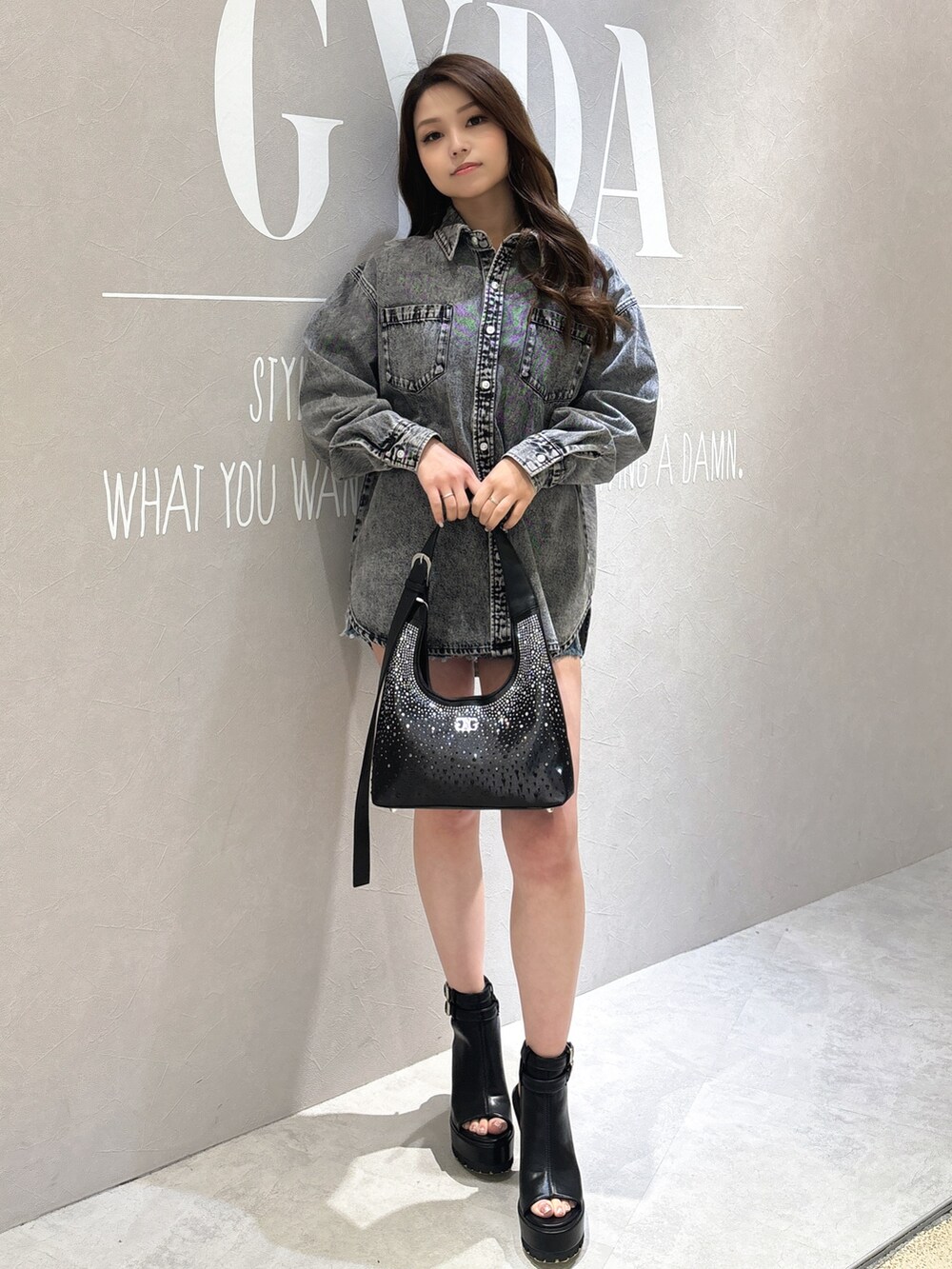 ブラック系のシャツ/ブラウス、ブラック系のブーツ、ブラック系のハンドバッグを着用したレディースの春コーディネートの2枚目の写真