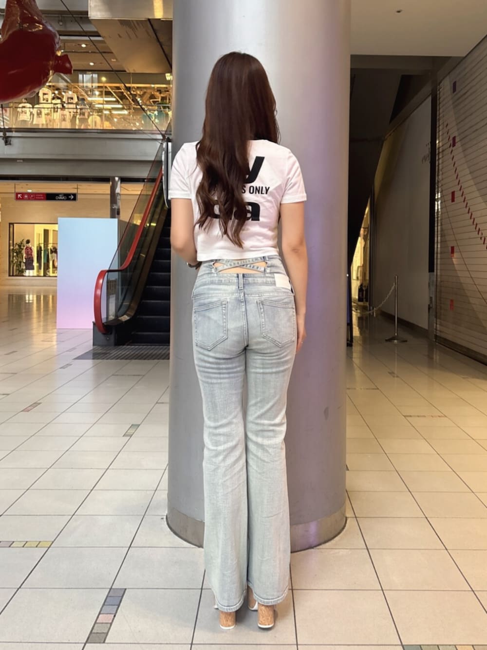 ブルー系のデニムパンツ、ホワイト系のサンダル、ホワイト系のTシャツ/カットソーを着用したレディースの夏コーディネートの3枚目の写真
