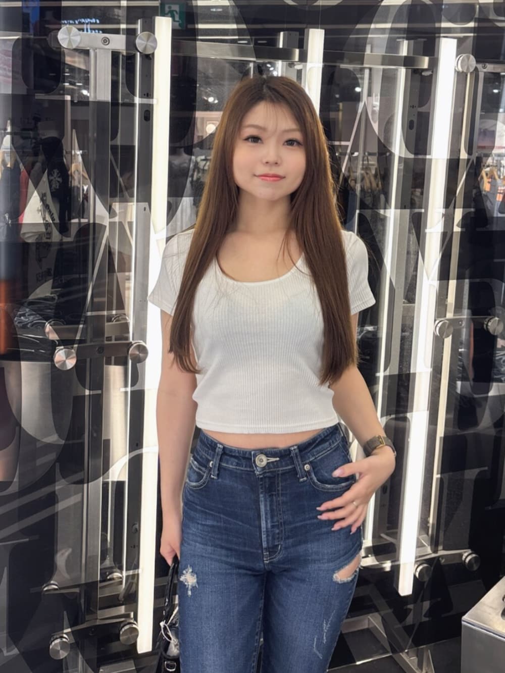 ホワイト系のサンダル、ホワイト系のハンドバッグ、ブルー系のデニムパンツを着用したレディースの夏コーディネートの4枚目の写真