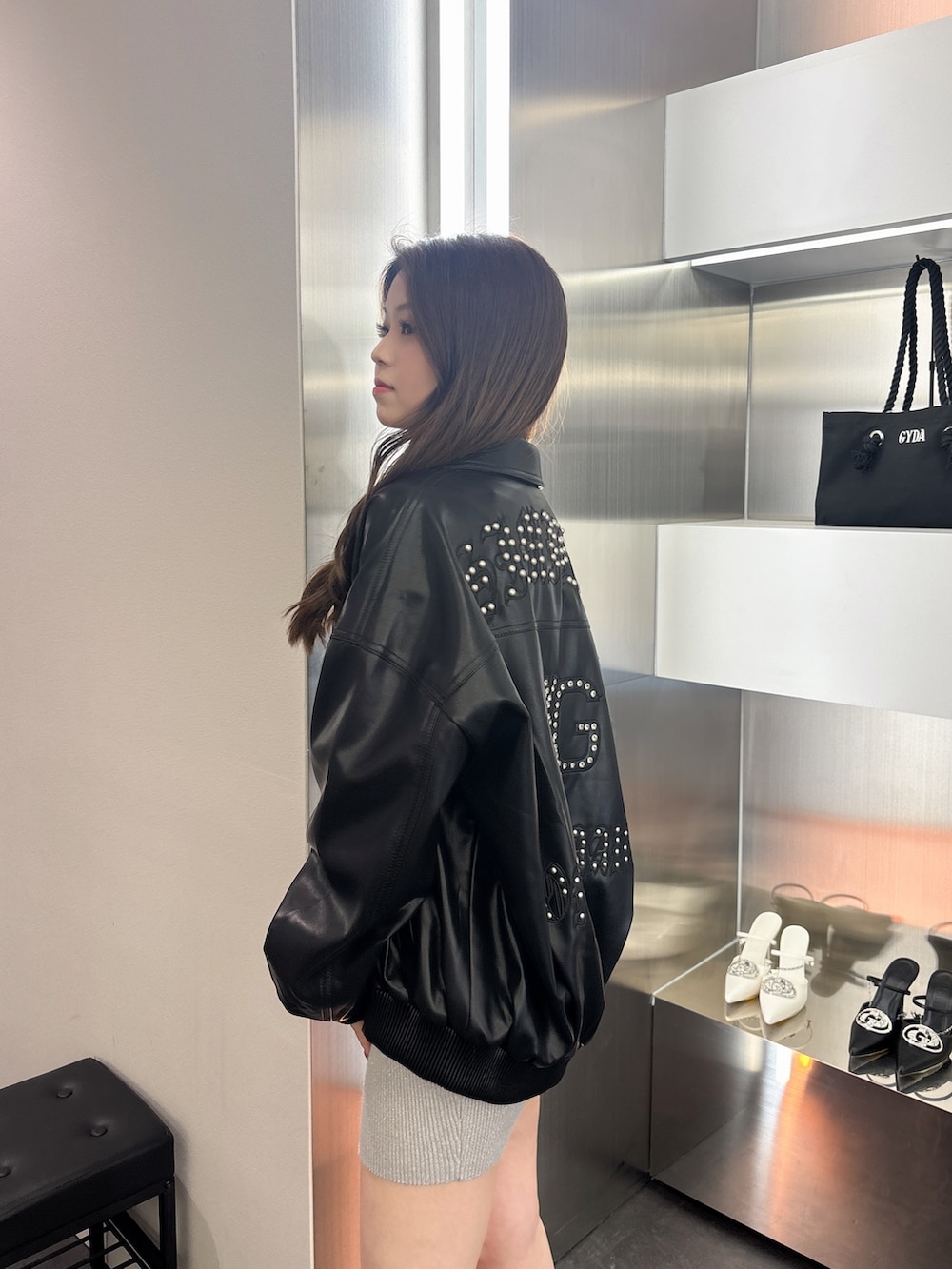 シルバー系のワンピース、ブラック系のブーツ、ブラック系のブルゾンを着用したレディースの春コーディネートの5枚目の写真