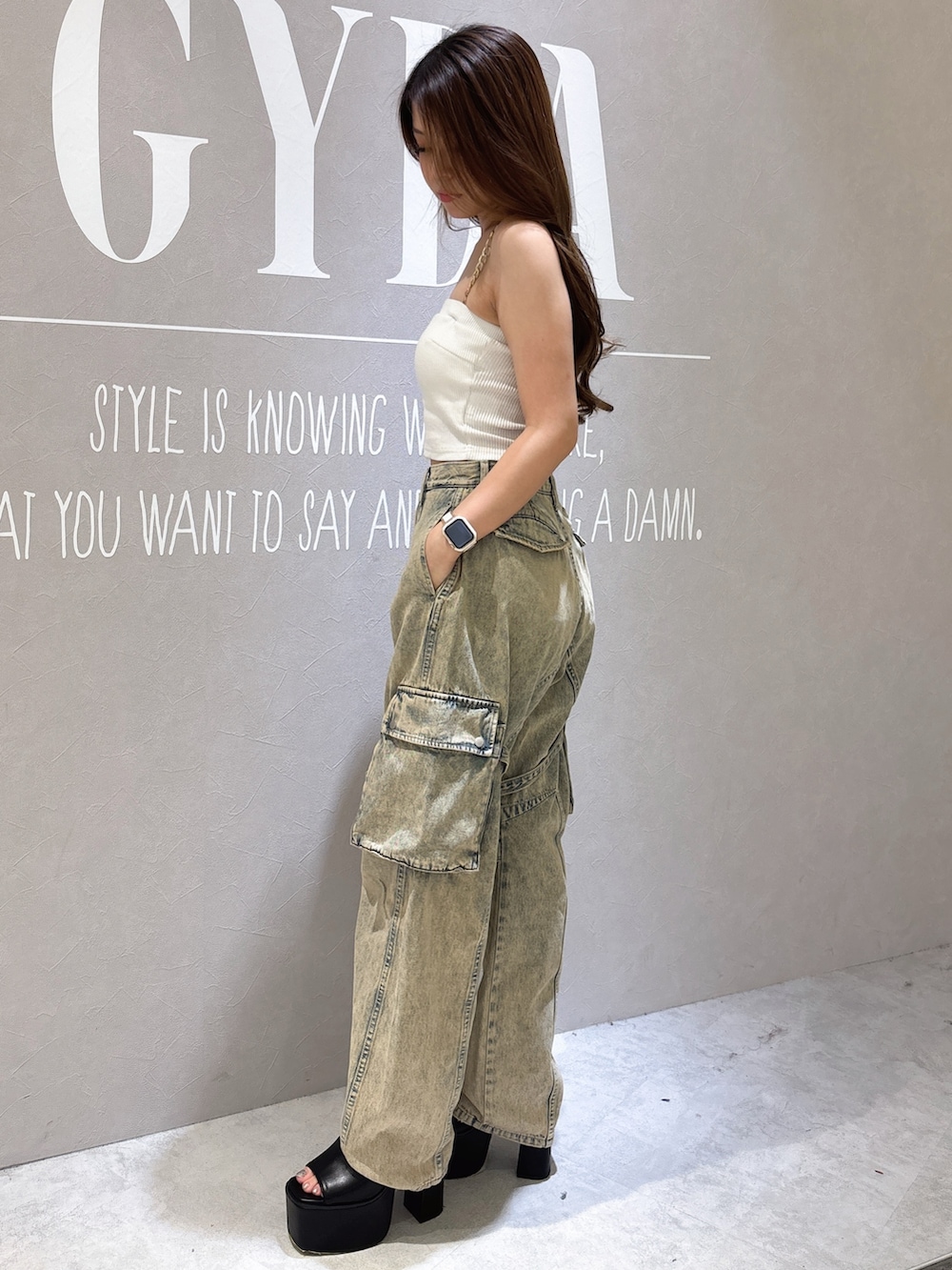 ホワイト系のキャミソール、ブラック系のサンダル、ブルー系のデニムパンツを着用したレディースの夏コーディネートの2枚目の写真