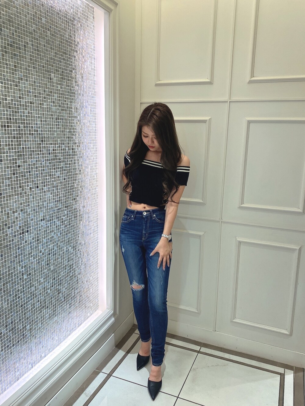 ブラック系のニット/セーター、ブルー系のデニムパンツ、ブラック系のパンプスを着用したレディースの夏コーディネートの2枚目の写真