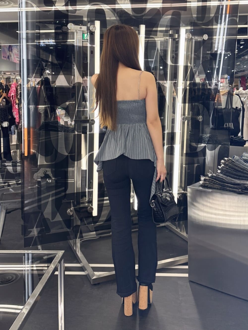 ブルー系のデニムパンツ、ホワイト系のサンダル、ホワイト系のハンドバッグを着用したレディースの夏コーディネートの3枚目の写真