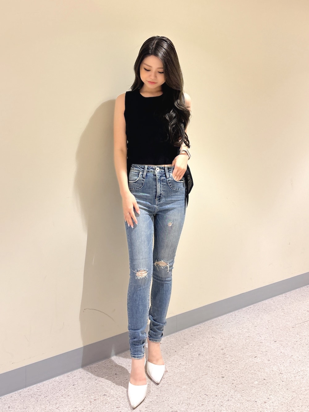 ブラック系のニット/セーター、ブルー系のデニムパンツ、ホワイト系のパンプスを着用したレディースの夏コーディネートの2枚目の写真