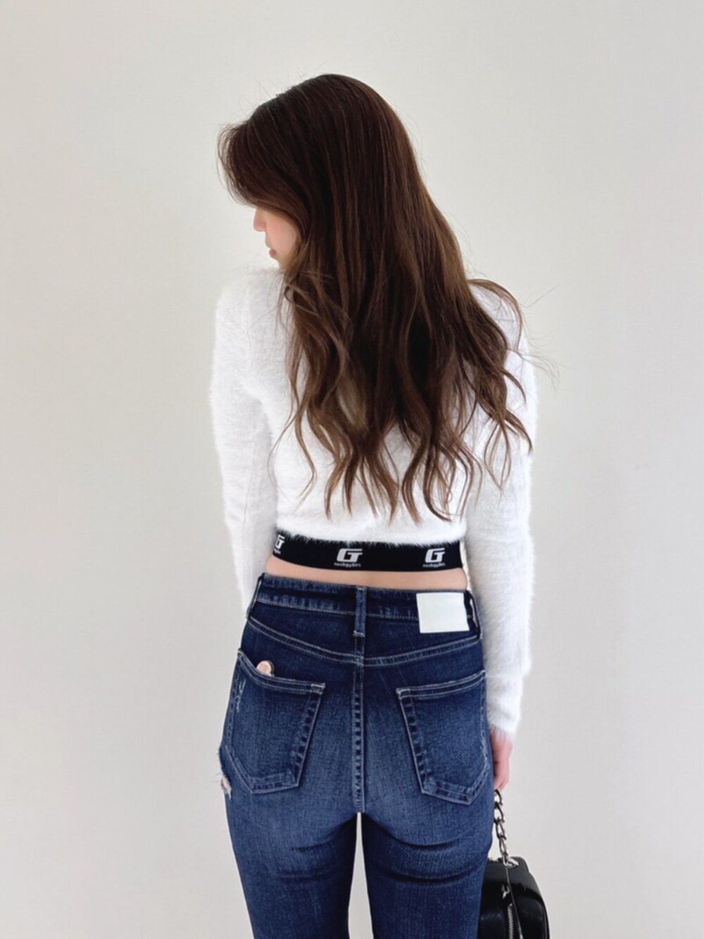 ホワイト系のパンプス、ブルー系のデニムパンツ、ブラック系のショルダーバッグを着用したレディースの冬コーディネートの8枚目の写真