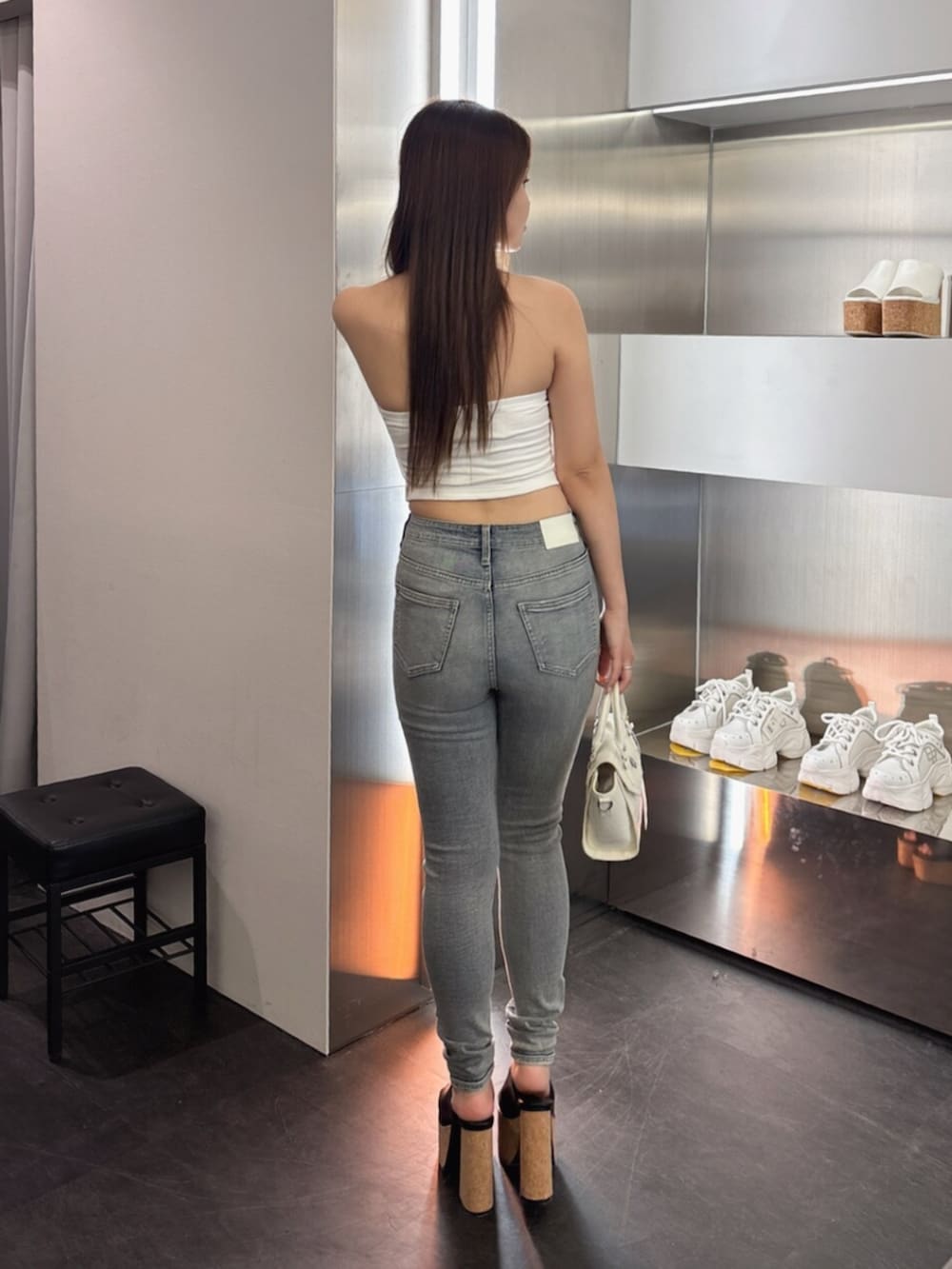 ホワイト系のサンダル、ホワイト系のハンドバッグ、ブルー系のデニムパンツを着用したレディースの夏コーディネートの3枚目の写真