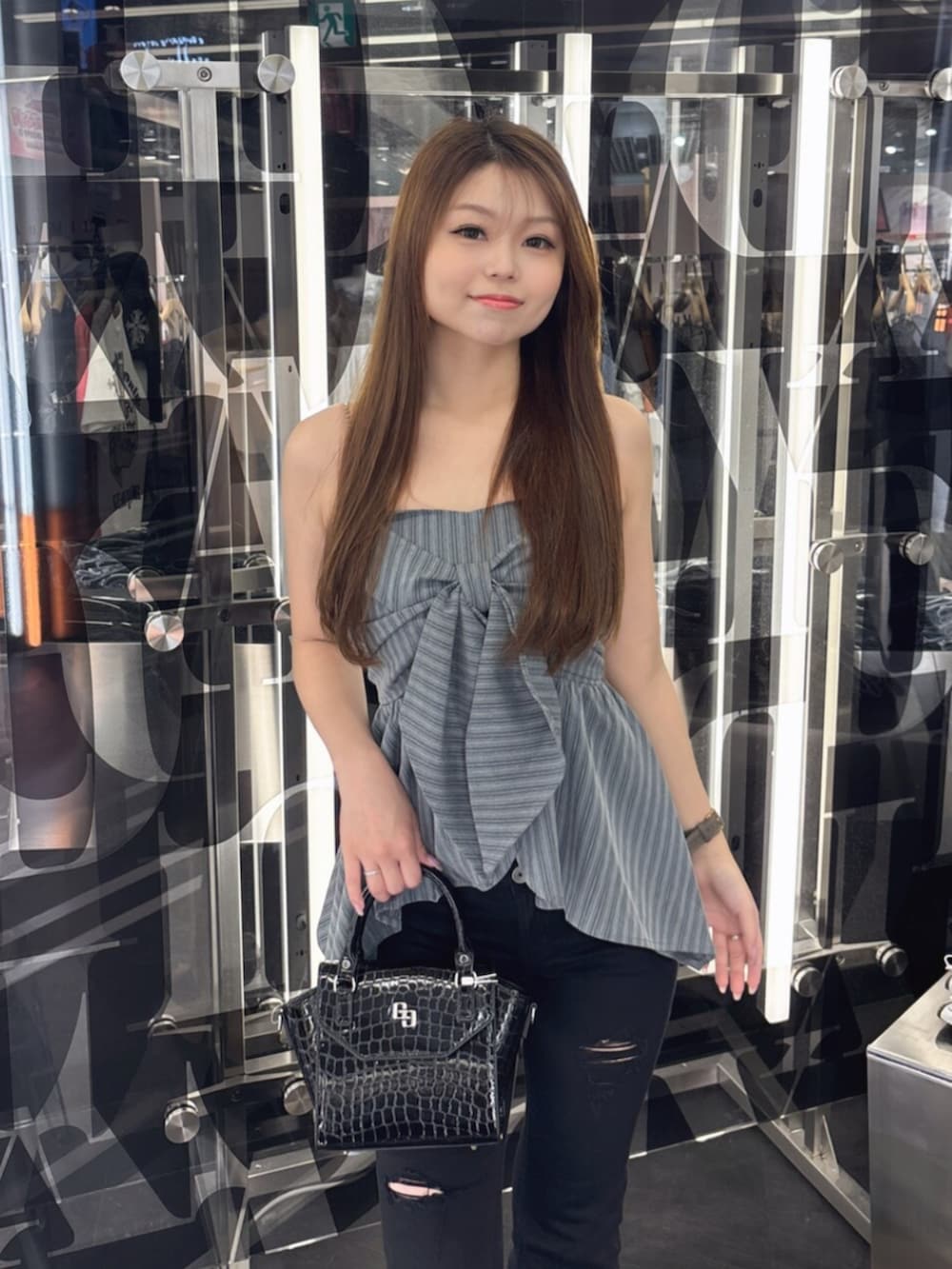ブルー系のデニムパンツ、ホワイト系のサンダル、ホワイト系のハンドバッグを着用したレディースの夏コーディネートの4枚目の写真