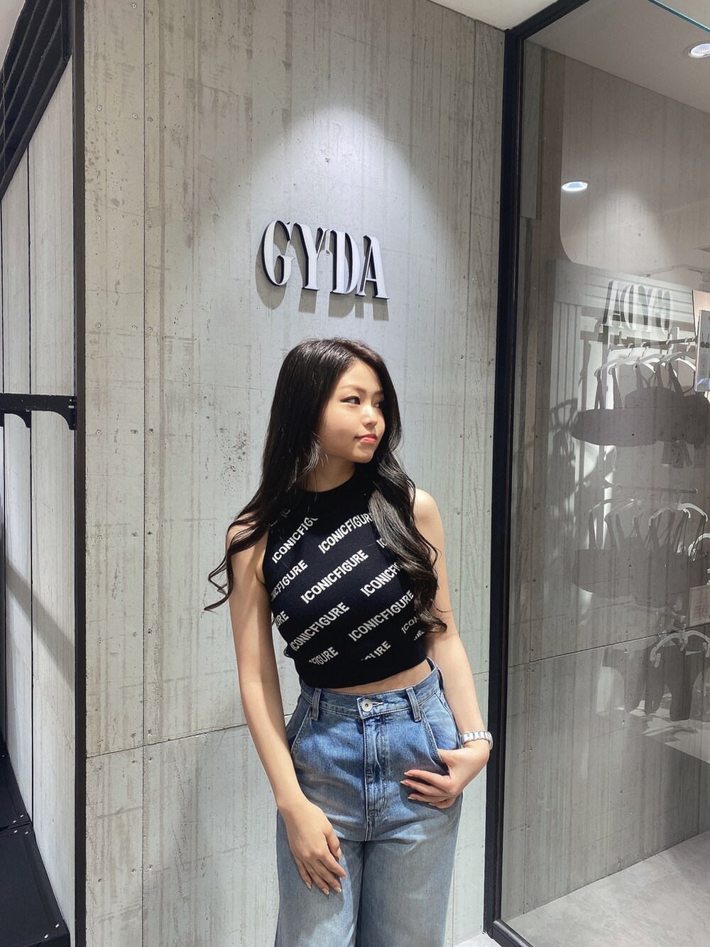 ブラック系のニット/セーター、ホワイト系のサンダル、ブルー系のデニムパンツを着用したレディースの春コーディネートの6枚目の写真