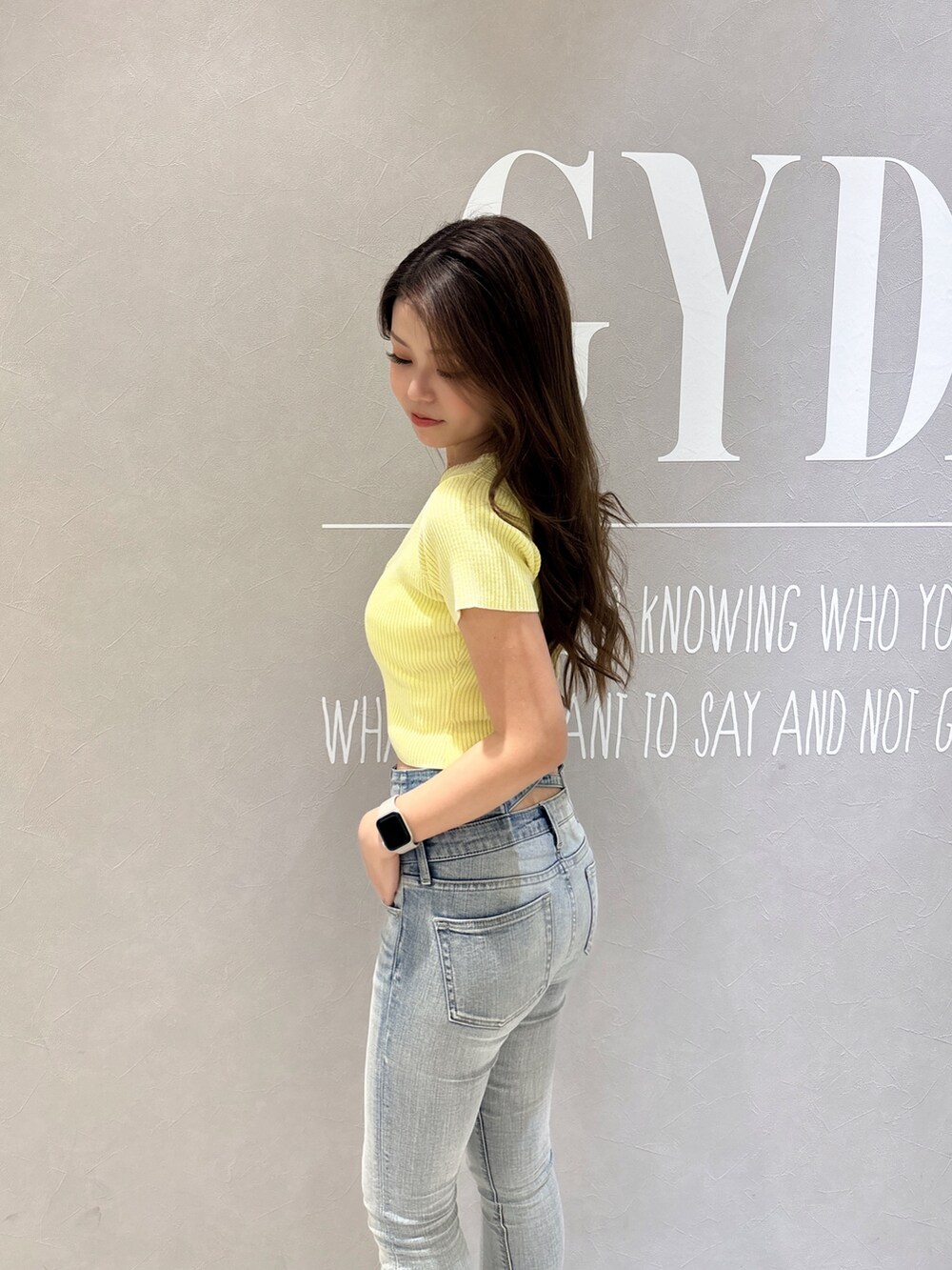 イエロー系のニット/セーター、ブルー系のデニムパンツ、ホワイト系のパンプスを着用したレディースの春コーディネートの5枚目の写真