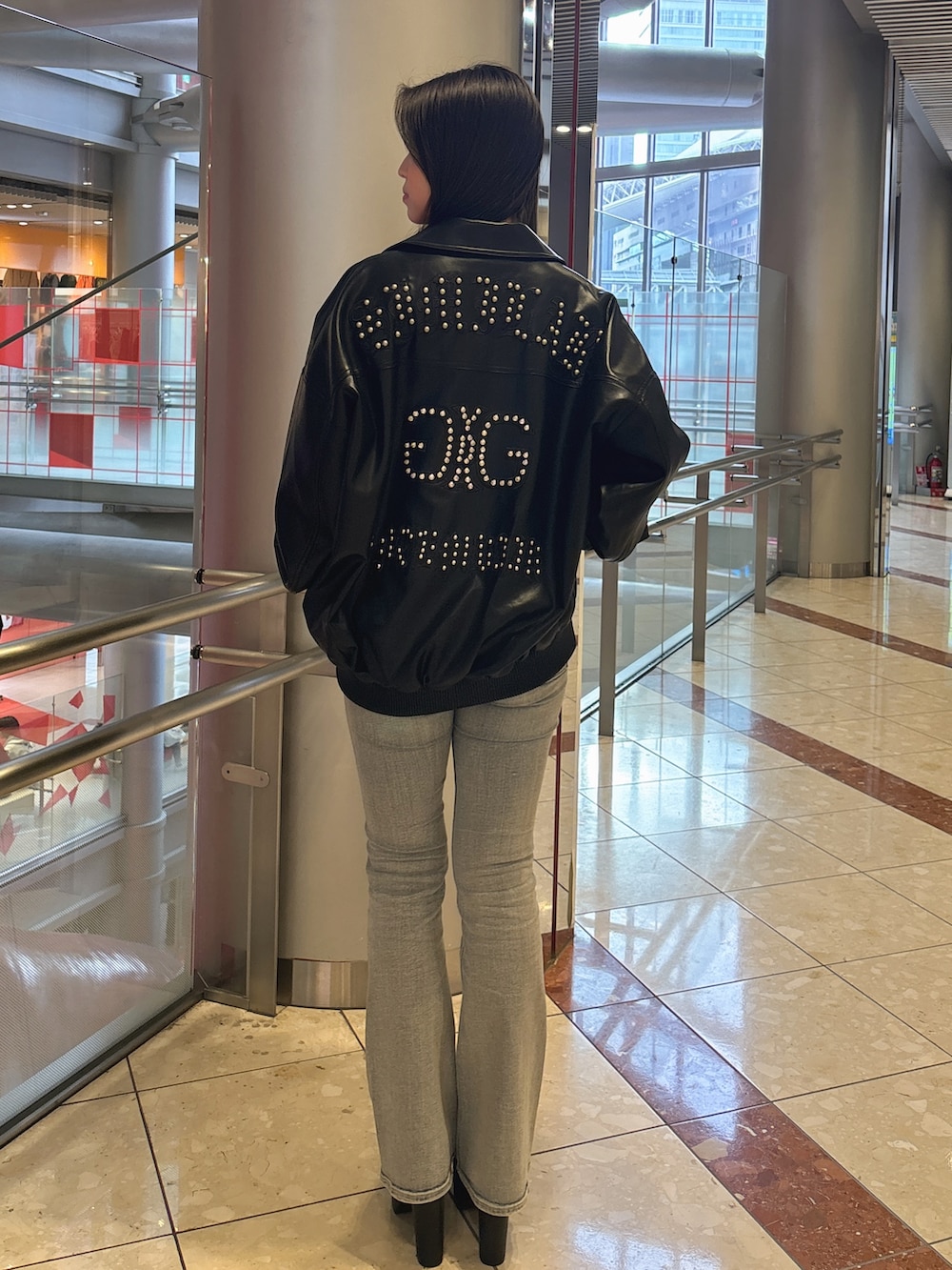 ブラック系のブルゾン、ブルー系のデニムパンツ、ブラック系のブーツを着用したレディースの春コーディネートの3枚目の写真