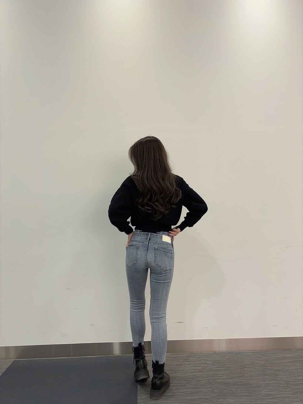 ブラック系のニット/セーター、ブルー系のデニムパンツ、ブラック系のブーツを着用したレディースの冬コーディネートの4枚目の写真