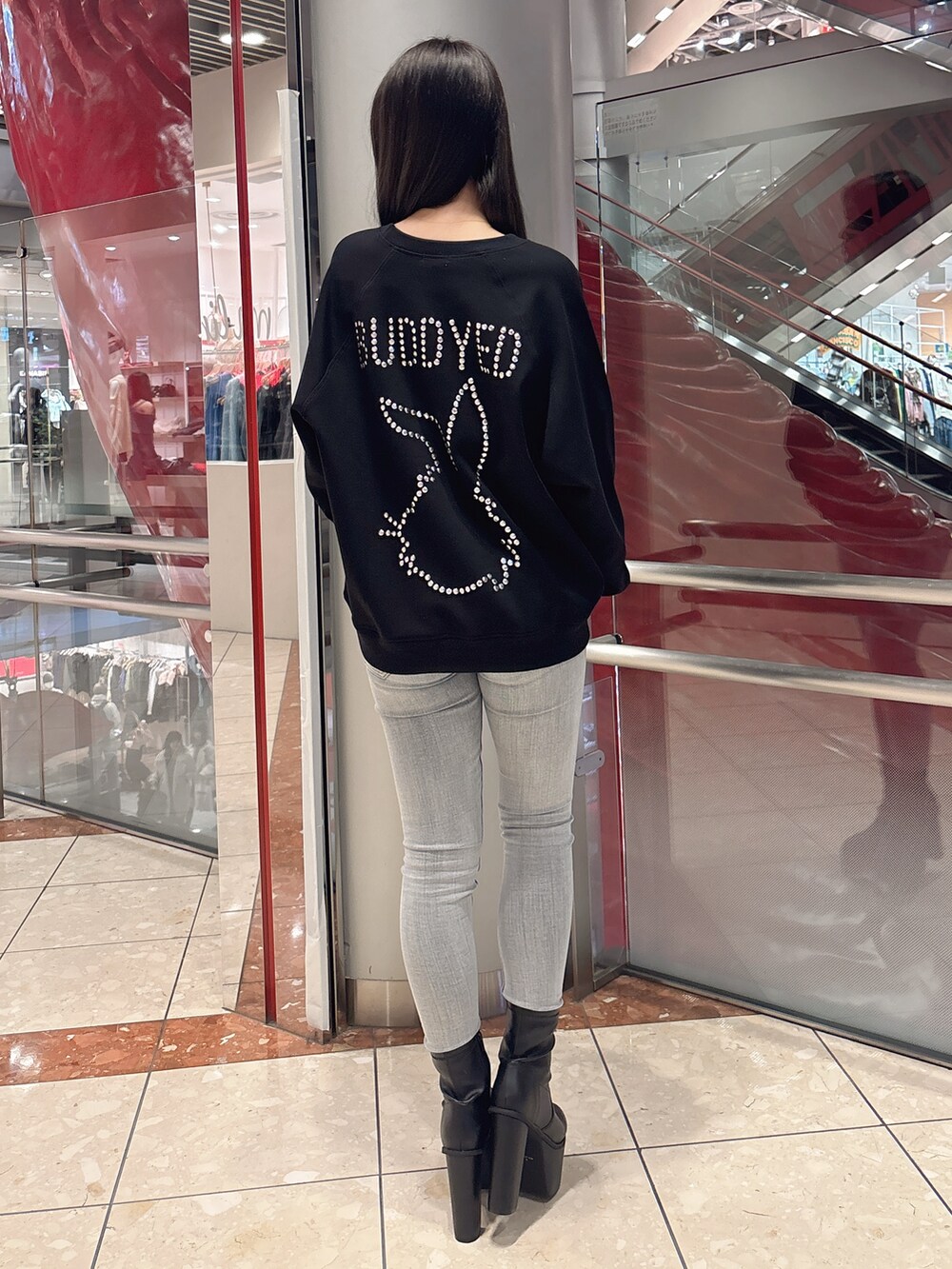 ブラック系のスウェット、ブルー系のデニムパンツ、ブラック系のブーツを着用したレディースの冬コーディネートの3枚目の写真