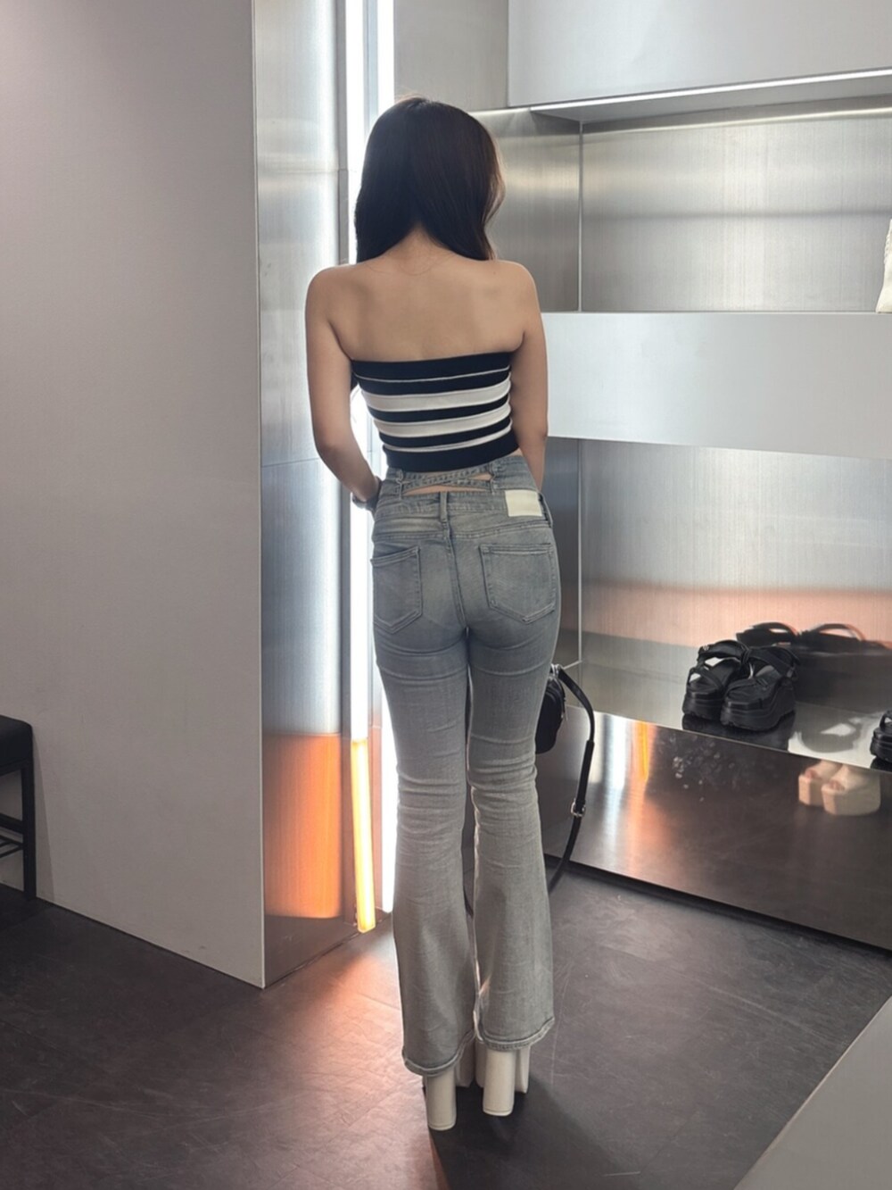 ブルー系のデニムパンツ、ホワイト系のサンダル、ブラック系のハンドバッグを着用したレディースの夏コーディネートの3枚目の写真