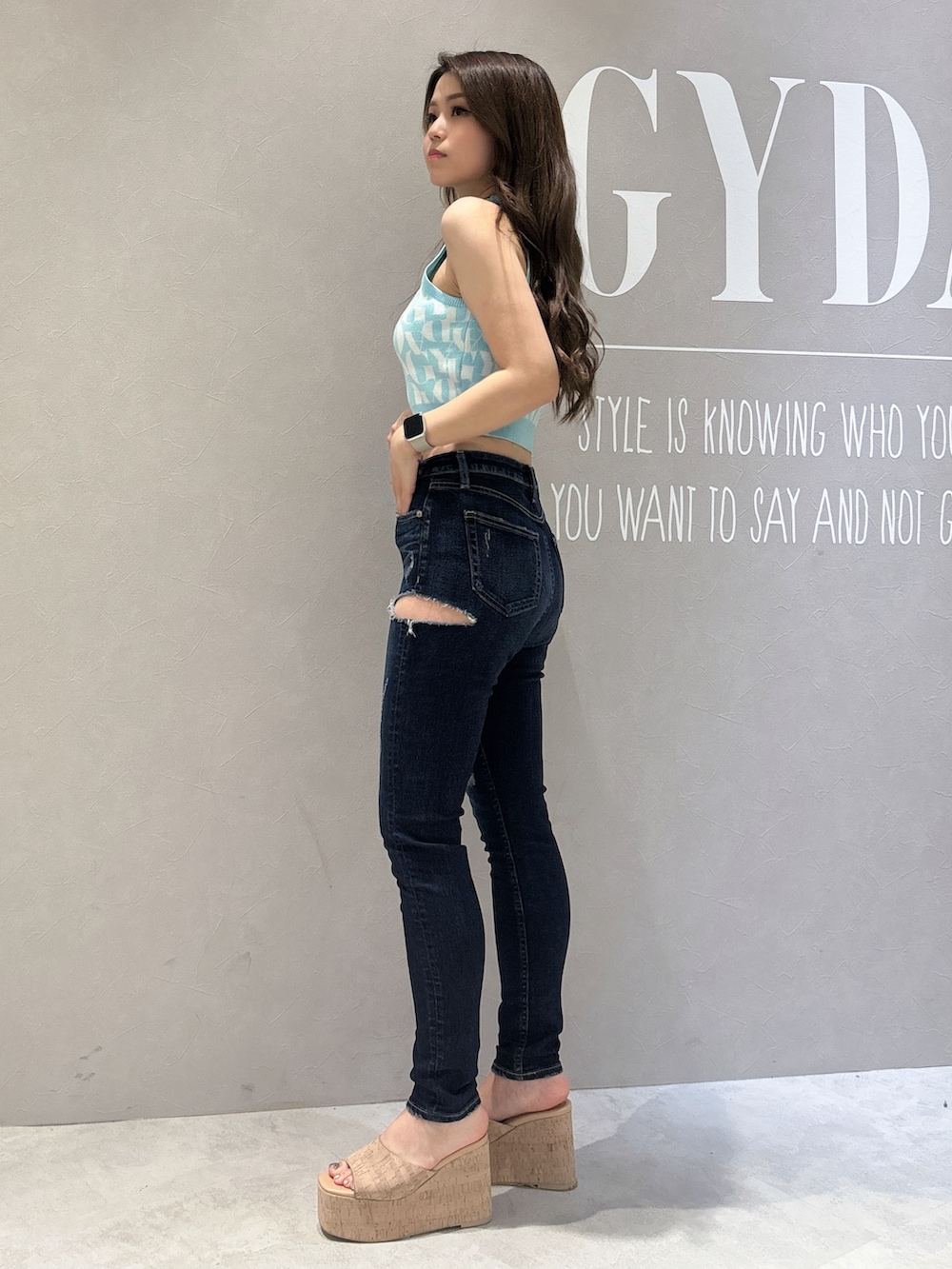 グリーン系のニット/セーター、ブルー系のデニムパンツ、ホワイト系のサンダルを着用したレディースの春コーディネートの2枚目の写真