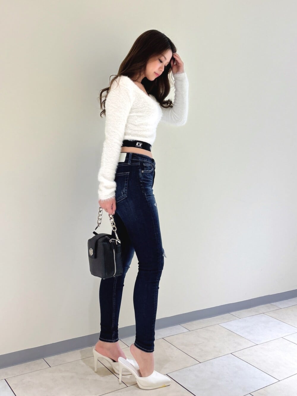 ホワイト系のパンプス、ブルー系のデニムパンツ、ブラック系のショルダーバッグを着用したレディースの冬コーディネートの5枚目の写真