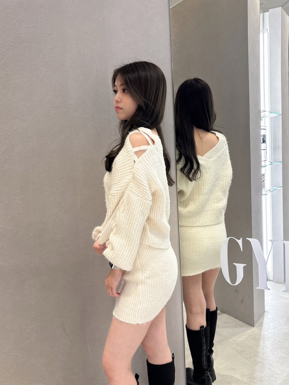 ホワイト系のニット/セーター、ホワイト系のスカート、ブラック系のブーツを着用したレディースの秋コーディネートの5枚目の写真