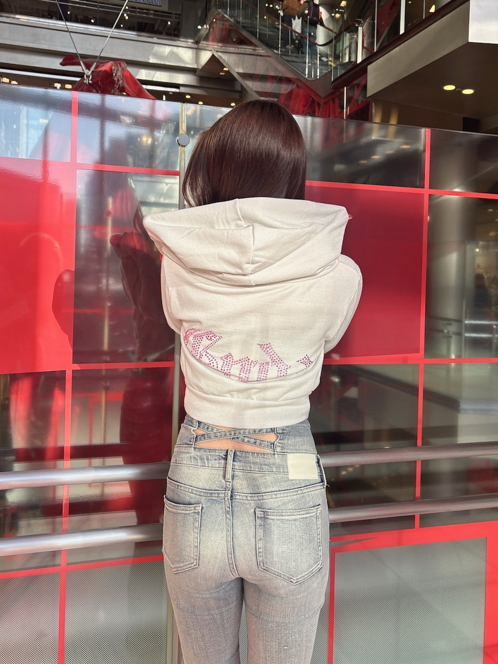 ホワイト系のパーカー、ブルー系のデニムパンツ、ブラック系のブーツを着用したレディースの冬コーディネートの6枚目の写真