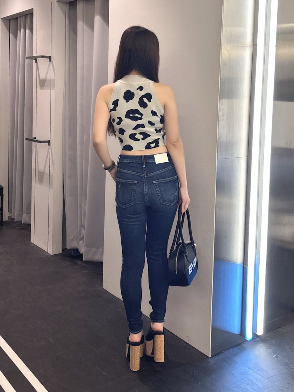 ブルー系のデニムパンツ、ホワイト系のサンダル、ピンク系のボストンバッグを着用したレディースの夏コーディネートの3枚目の写真