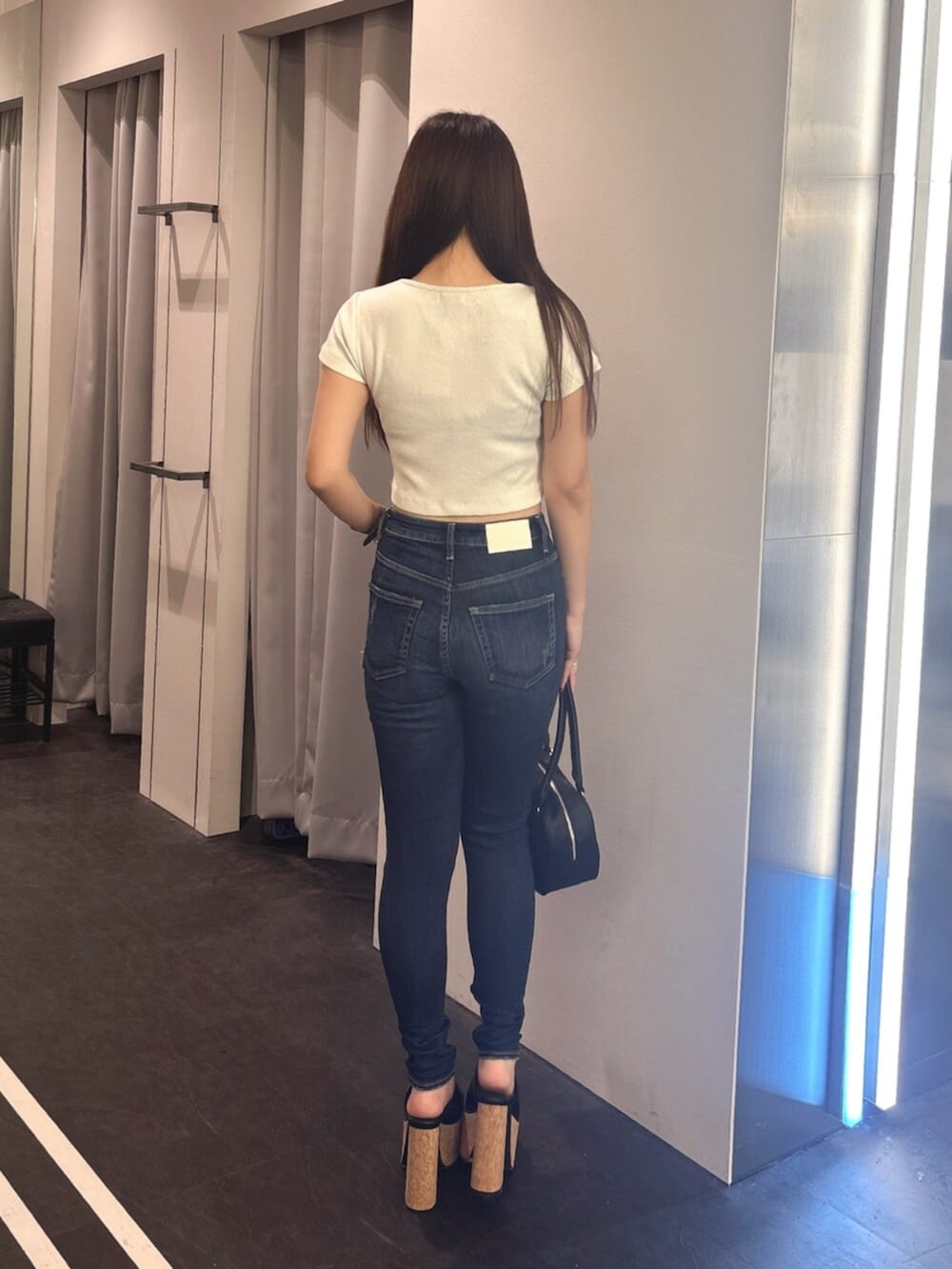 ブルー系のデニムパンツ、ホワイト系のサンダル、ホワイト系のTシャツ/カットソーを着用したレディースの夏コーディネートの3枚目の写真