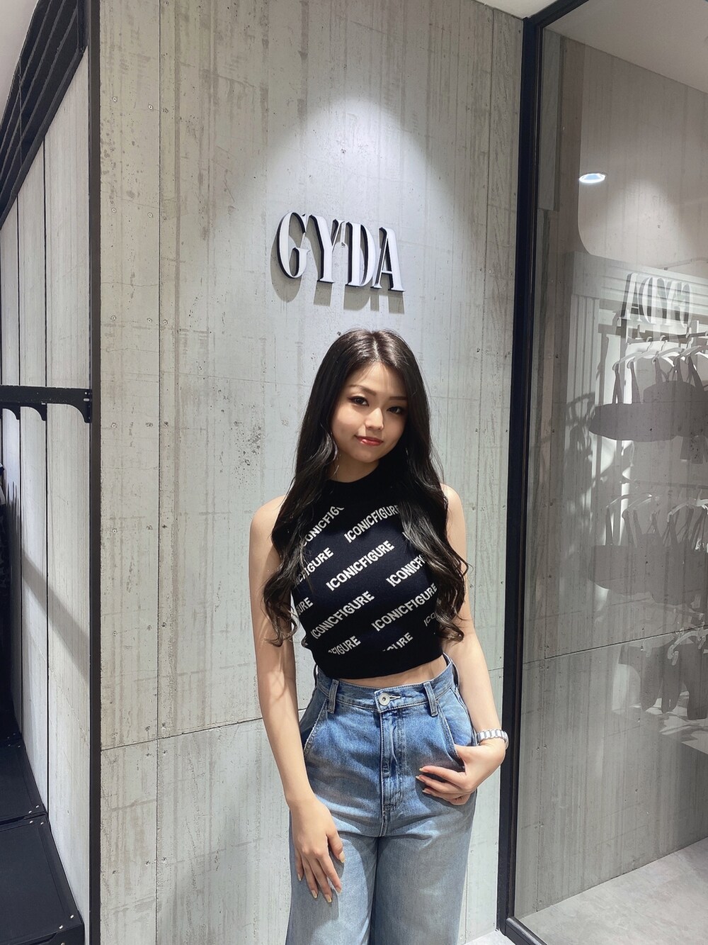 ブラック系のニット/セーター、ホワイト系のサンダル、ブルー系のデニムパンツを着用したレディースの春コーディネートの5枚目の写真