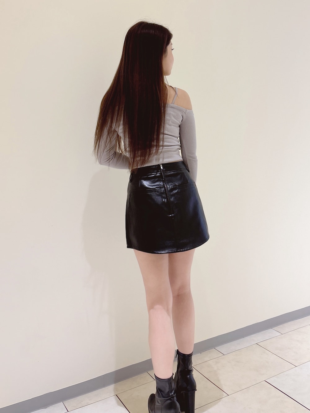 グレー系のTシャツ/カットソー、ブラック系のスカート、ブラック系のブーツを着用したレディースの秋コーディネートの4枚目の写真