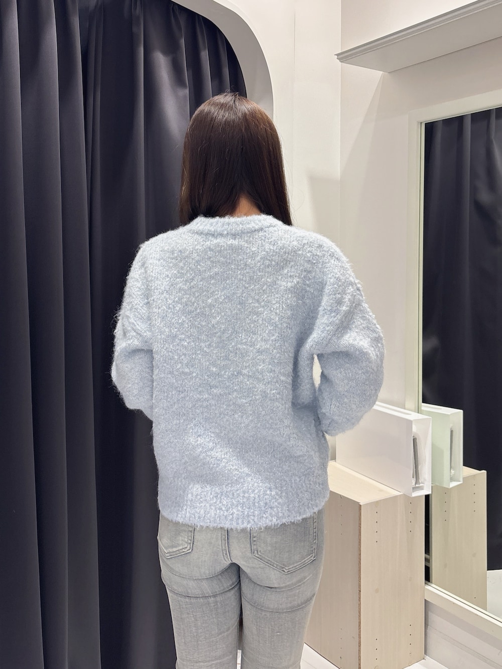 ブルー系のニット/セーター、ブルー系のデニムパンツ、ブラック系のブーツを着用したレディースの冬コーディネートの6枚目の写真