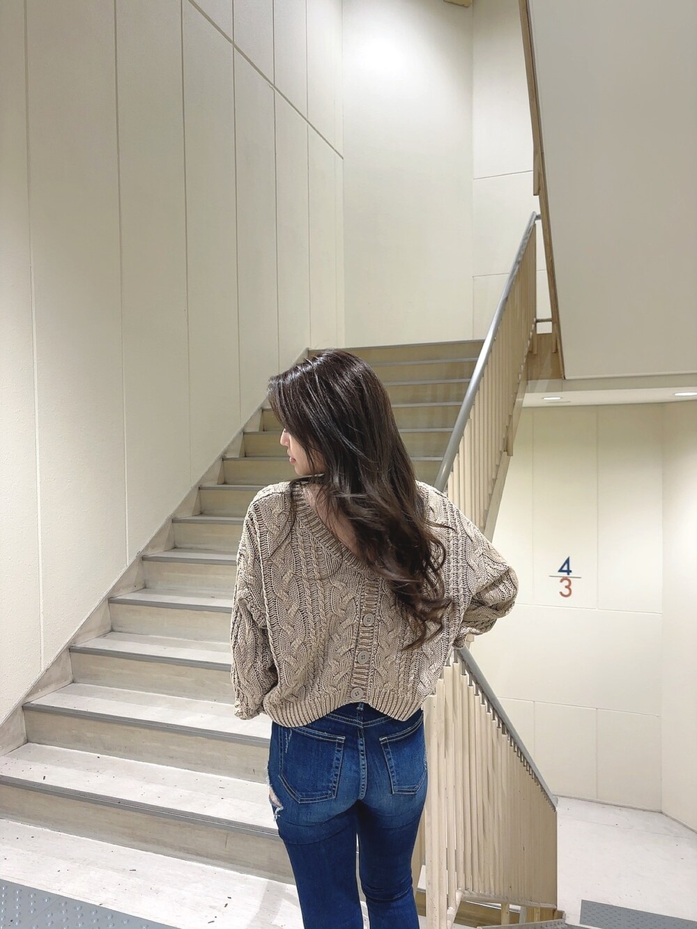 ベージュ系のニット/セーター、ブルー系のデニムパンツ、ホワイト系のパンプスを着用したレディースの冬コーディネートの6枚目の写真