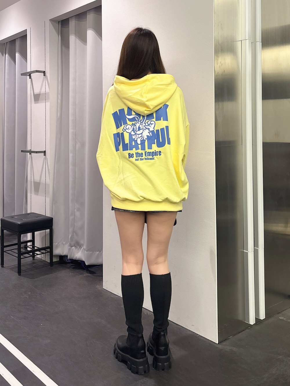 イエロー系のパーカー、ブラック系のハンドバッグ、ブラック系のブーツを着用したレディースの秋コーディネートの3枚目の写真