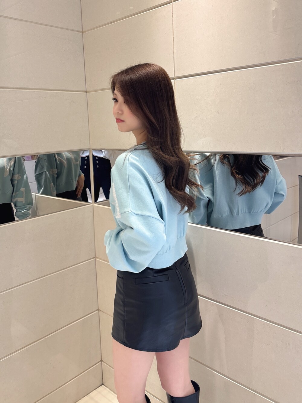 ブルー系のニット/セーター、ブラック系のスカート、ブラック系のブーツを着用したレディースの冬コーディネートの5枚目の写真