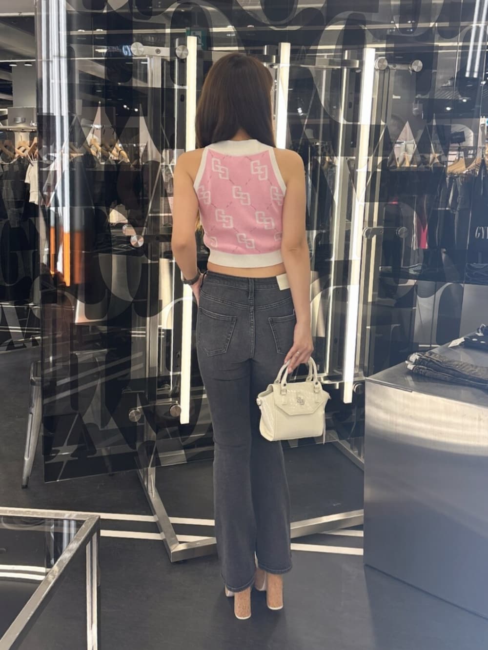 ホワイト系のサンダル、ブラック系のデニムパンツ、ホワイト系のハンドバッグを着用したレディースの夏コーディネートの3枚目の写真